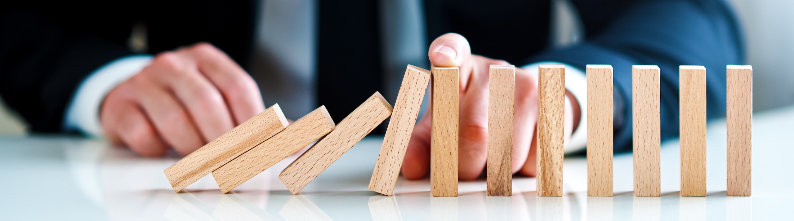 businessman stops falling wooden blocks. business solutions concept